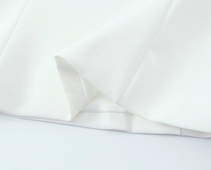 Close-up of fine white fabric texture and precision stitching on the garment hem