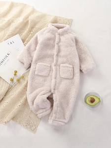 Pink plush baby romper for winter with front buttons and pockets on a lace blanket