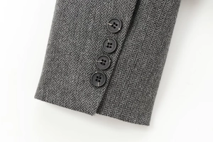 Detail of grey herringbone wool sleeve cuff with four classic black buttons on blazer