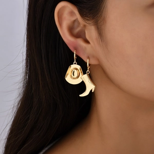 Golden cowboy boot and hat asymmetric drop earrings worn by model with high polish finish
