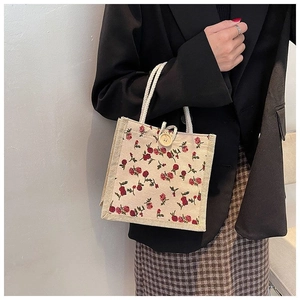 Detail of floral canvas tote bag with cotton rope handles and a wooden button closure