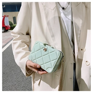 Detail of mint green quilted PVC jelly bag with gold flower clasp and chain strap