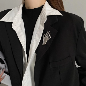 Close-up of polished silver hand brooch on a black suit lapel for a stylish look