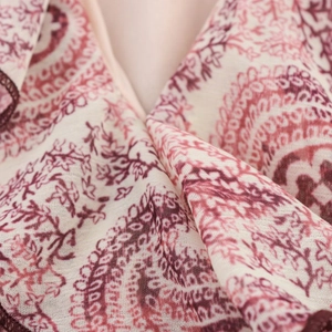 Close-up of red paisley print on beige fabric showing detailed textile texture and pattern