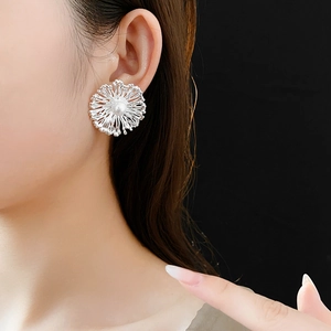 Close-up of elegant silver flower earring with pearl center worn by a model