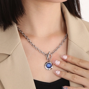 Detail view of silver O-chain necklace with a blue faceted crystal pendant and OT clasp