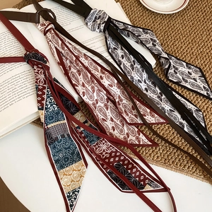 Close-up of bohemian silk scarves with leather tassels and paisley patterns on a book