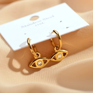 Detail view of 316L gold stainless steel evil eye earrings on silk background
