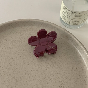Détail d'une pince à cheveux fleur en acétate rouge foncé avec lettrage Handmade