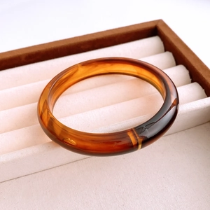 Detailed view of vintage amber resin bangle with retro marbled texture on display tray
