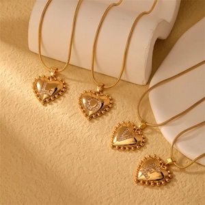 Detail of four golden heart pendants with LOVE rhinestones on sleek snake chains
