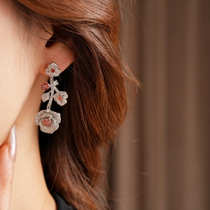 Macro detail of vintage floral earrings with silver metal, white pavé and red square stones
