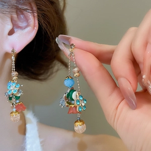 Close-up of crystal flower tassel earrings with blue rhinestones and beads on a model