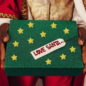 Boîte cadeau pailletée verte avec étoiles dorées et étiquette Love Santa dans les mains