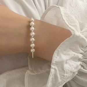 Detailed view of elegant freshwater pearls and gold-plated toggle clasp on woman's wrist