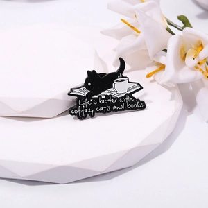 Detail of black cat enamel pin featuring coffee and books with meaningful quote