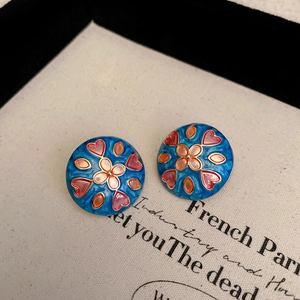 Close-up of vintage round blue enamel stud earrings with colorful heart floral patterns