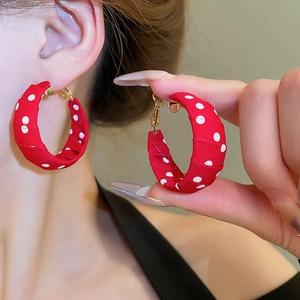 Close-up of red polka dot fabric wrapped hoop earrings on ear for size comparison
