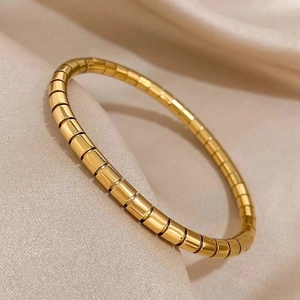 Polished gold bamboo style titanium steel bangle on champagne silk background