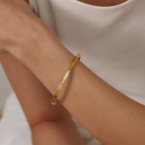 Macro detail of 18K gold geometric bangle featuring five sparkling inset zircons on wrist
