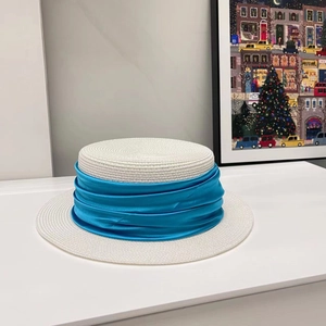 Detail of white flat top straw hat featuring a luxury royal blue pleated satin ribbon band