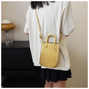 Detail of gold faux leather handbag with crocodile pattern and creative snake handle