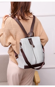 Detail of light gray PU leather backpack with lychee texture and brown straps