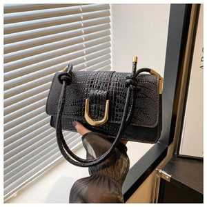 Detail of black faux crocodile skin handbag with elegant gold U-shaped metal buckle closure