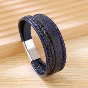 Detail of multi-layer braided leather bracelet with silver magnetic clasp on wood