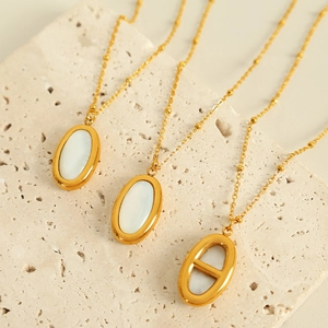 Elegant gold necklaces with white oval shell pendants on a textured stone base