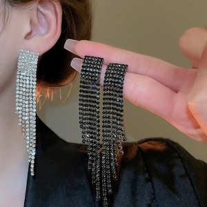 Détail de boucles d'oreilles à longs pompons argent et noir avec strass scintillants