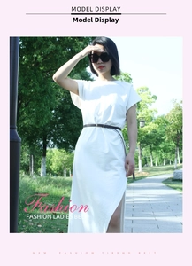 Detail of slim dark brown PU leather belt with gold pin buckle on white dress