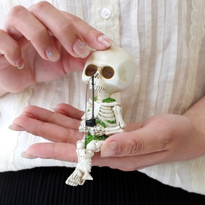 Close-up of a resin fishing skeleton figurine held in hands to show miniature scale