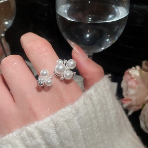 Detailed view of elegant pearl and zircon cluster ring on hand with a soft knit background