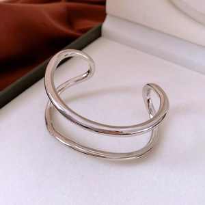 Detail of silver double-layered wavy open bangle in a gift box with silk fabric