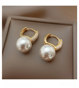 Close-up of golden pearl earrings with crystal inlay on a professional jewelry display