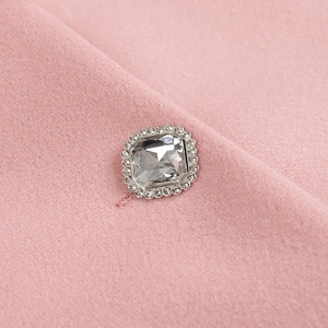 Détail de la boucle carrée en strass sur manteau en laine rose avec finition argentée