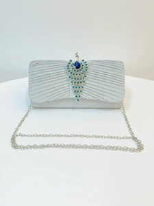 Detail of silver pleated evening clutch bag with a crystal-encrusted peacock clasp