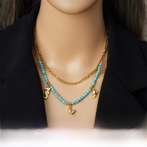 Detail of layered gold seahorse and starfish pendants with turquoise beaded chain necklace