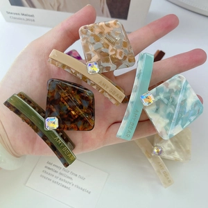 Detailed close-up of acetate hair clips with rhinestone inlay and marbled pattern