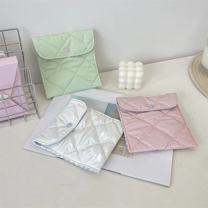 Close-up of quilted storage pouches in mint, white, and pink with heart-shaped buttons