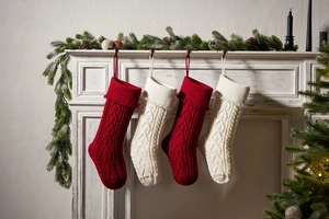 Close-up of red and cream knitted Christmas stockings with heart tassels by a fireplace