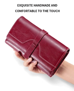 Close-up of red oil wax leather long wallet with white stitching and strap closure