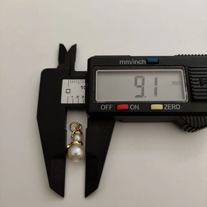 Detail showing measurement of snowman pearl pendant width with digital caliper