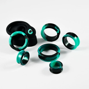 Detail of black and green marble silicone ear gauges set on a model ear display