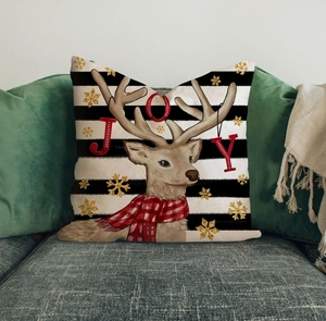 Detail of Christmas reindeer pillow cover with JOY text and gold snowflakes on gray sofa