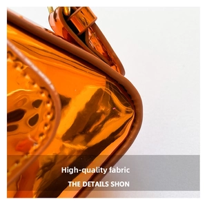 Macro shot of orange glossy patent leather bag with premium stitching and brown trim