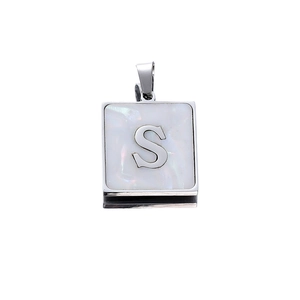Macro detail of square stainless steel pendant with white pearl inlay and letter S