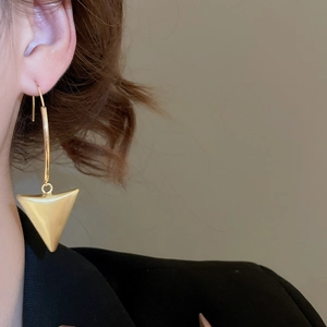 Close-up of 18k brushed gold geometric triangle pendant earrings worn on model
