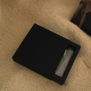 Minimalist black square jewelry storage box with clear window and golden necklace display